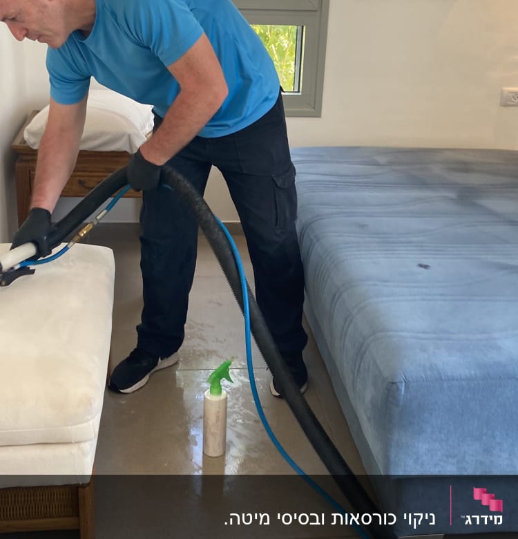 אדם מנקה ספה עם מכשיר שאיבה וצינור